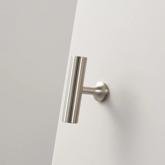 T-model mat-nikkel meubelknop met ribbels aan de zijkant op en witte kast.