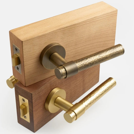 Twee deurkrukken gehamerd brons en mat messing op houten blokjes