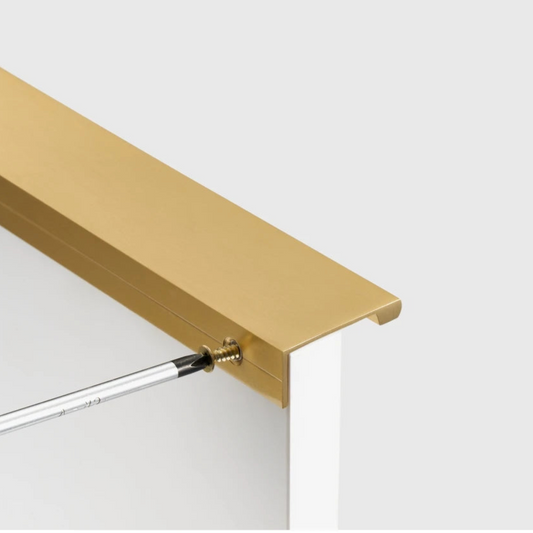 bevestiging met een schroevendraaier van een haakse model meubelgreep op een witte kast.