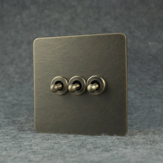 vierkante vintage lichtschakelaar met 3 toggle op een grijs vilten ondergrond