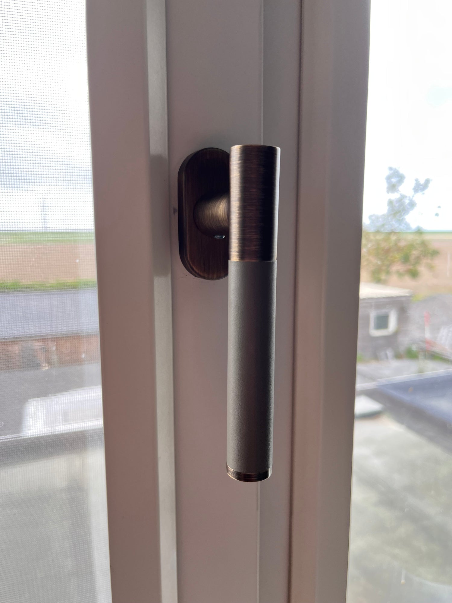 Raamkruk brons en leer op wit kozijn