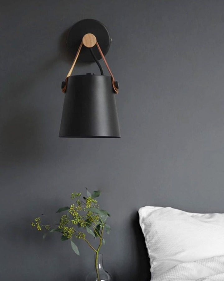 wandlamp met zwart kapje met leer hangend aan een houten stok