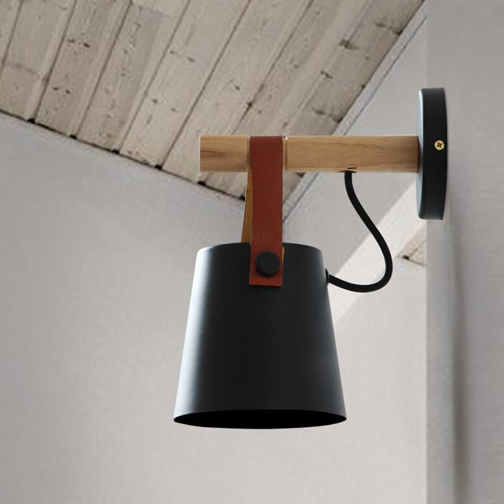 wandlamp met zwart kapje met leer hangend aan een houten stok