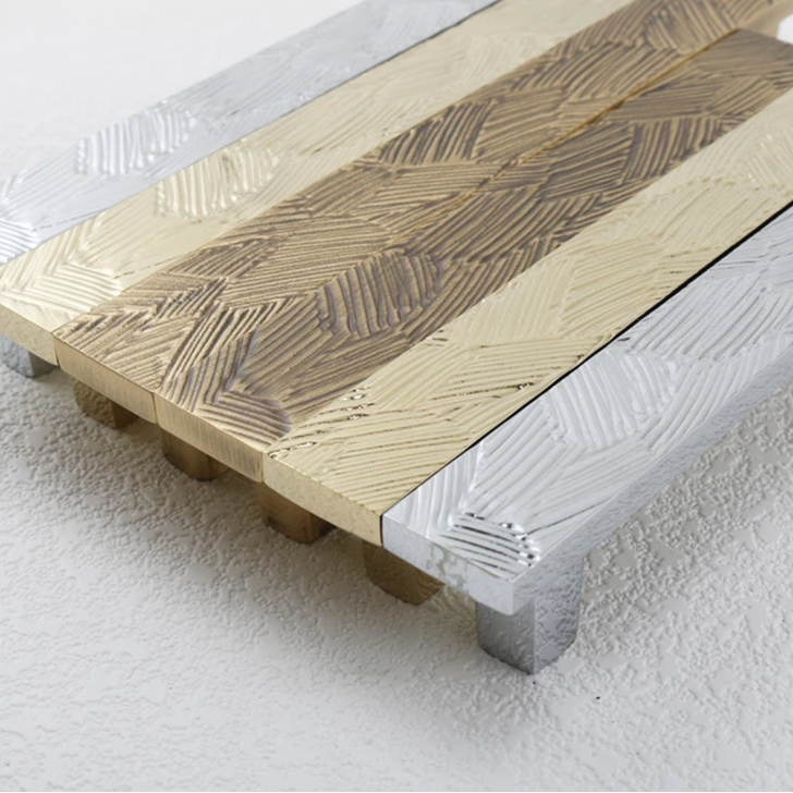 overzicht van langwerpige vlakke meubelgrepen met abstract geometrisch patroon in goud, chroom en brons 