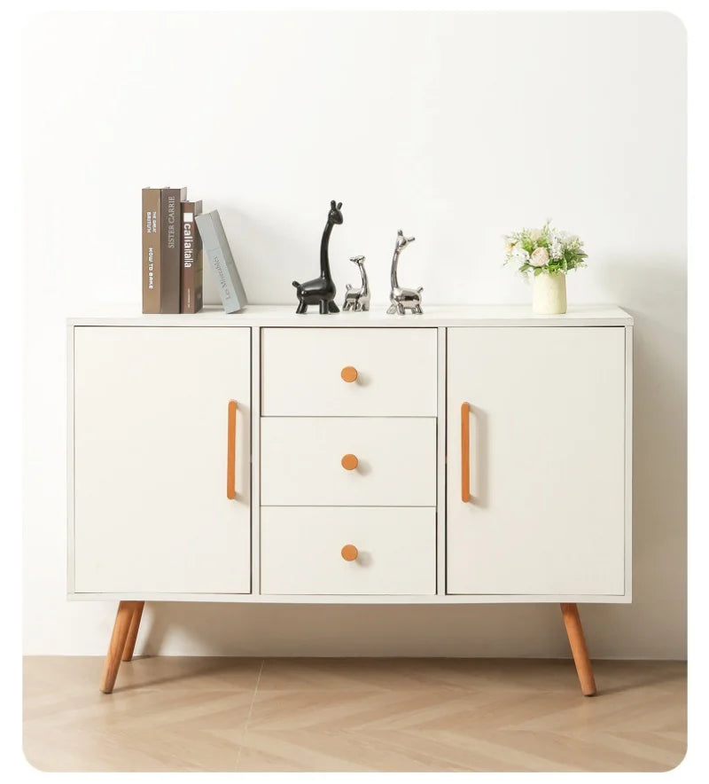 Strakke witte kast met twee deurtjes aan weerszijde en  lades in het midden. Op de kast meubelgreepjes en knopjes in berkenhout.