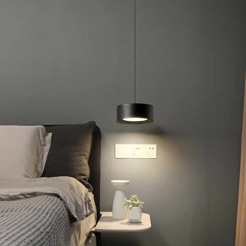 zwarte ronde hanglamp naast een bed