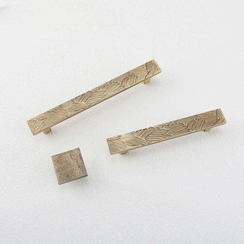 overzicht van rechthoekige meubelgrepen en vierkante meubelknop  met een abstract geometrisch patroon uitgevoerd in brons.