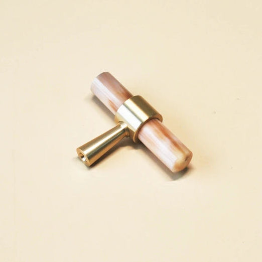 t-model meubelknop mat messing en wit hoorn liggend op een beige ondergrond