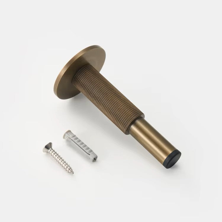 detail foto van een brons kleurige deurstop liggend op een witte ondergrond