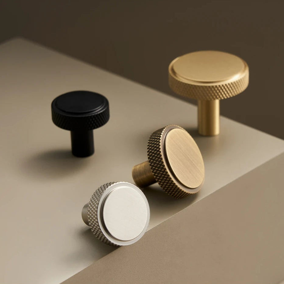 4 meuelknopjes in verschillende kleuren met een knurled rand op een taupe ondergrond